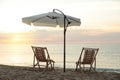 Wooden deck chairs and outdoor umbrella on sandy beach at sunset. Summer vacation Royalty Free Stock Photo