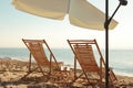 Wooden deck chairs, outdoor umbrella and table with cocktails on sandy beach. Summer vacation Royalty Free Stock Photo