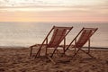 Wooden deck chairs on beach at sunset. Summer vacation Royalty Free Stock Photo