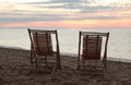 Wooden deck chairs on sandy beach at sunset. Summer vacation Royalty Free Stock Photo