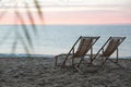 Wooden deck chairs on sandy beach at sunset. Summer vacation Royalty Free Stock Photo