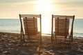Wooden deck chairs on sandy beach at sunset. Summer vacation Royalty Free Stock Photo