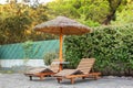 Wooden deck chairs under a straw umbrella Royalty Free Stock Photo