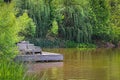 Wooden deck with comfortable rustic chairs jutting out into pond surrounded by lush greenery with coy swimming in water - Lazy Royalty Free Stock Photo