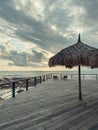 Wooden deck with straw beach umbrellas and sunset view Royalty Free Stock Photo