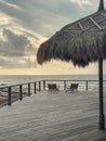 Wooden deck with straw beach umbrellas and sunset view Royalty Free Stock Photo