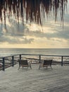 Wooden deck with straw beach umbrellas and sunset view Royalty Free Stock Photo