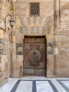 Wooden decorated copper plated door and stone bricks wall at the courtyard of Al-Sultan Barquq mosque, Old Cairo, Egypt