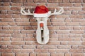 Wooden deer hanging on the wall with a Santa Claus hat and red nose Royalty Free Stock Photo