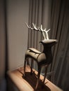 a wooden deer-shaped statue that stands upright under a bedroom lamp