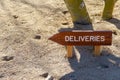 Wooden deliveries sign with arrow in the ground