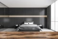 Wooden desk foreground and blurred dark bedroom with bed and linens Royalty Free Stock Photo