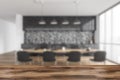 Wooden desk foreground with blurred grey and wooden dining room with furniture