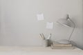 Wooden desk with lamp, books and cup holder for pencils. Note pad mockups taped on wall. Neutral stylish minimal Royalty Free Stock Photo