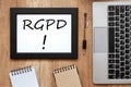 Wooden desk with a laptop, a black frame with RGPD inscription and notebooks