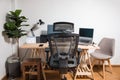 Wooden desk with laptop, display, mouse, lamp, ergonomic chair and artificial tree in workplace on bedroom