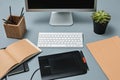 The gray desk with laptop, notepad with blank sheet, pot of flower, stylus and tablet for retouching Royalty Free Stock Photo