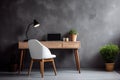 Wooden desk next to empty copy space gray stucco wall with items for work and chair, workplace at home or office. Royalty Free Stock Photo