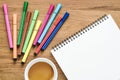 Wooden desk table with notebook, color pens and cup of coffee. T