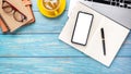 Wooden desk workplace with blank screen smart phone, laptop computer, pen, eyeglass, notebook and cup of coffee Royalty Free Stock Photo