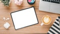 Wooden desk workplace with blank screen tablet, laptop, pen, notebook, earphone and cup of coffee Royalty Free Stock Photo