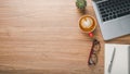 Wooden desk workplace with laptop computer, notebook. eyeglass, pen and cup of cofeee. Royalty Free Stock Photo