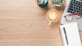 Wooden desk workplace with laptop computer, notebook, eyeglass, pen and cup of coffee Royalty Free Stock Photo