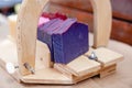 Wooden device for cutting soap handmade with a freshly cut purple bar of soap. Close up