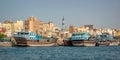 Wooden dhow cargo boats in Dubai Creek, old town in the background, UAE