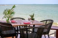 Wooden dining table with tableware and weave chairs on patio