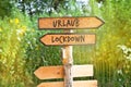 Wooden direction sign with the German word Urlaub vacation and Lockdown