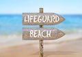 Wooden direction sign with lifeguard beach