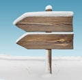Wooden direction sign with less snow and sky bg. two_arrows-one_direction Royalty Free Stock Photo
