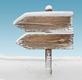 Wooden direction sign with snow and sky bg. two_arrows-one_direction Royalty Free Stock Photo