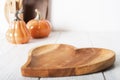 Wooden dish heart on light background. Serving, cooking, recipes for autumn dishes. Pumpkins in defocus.