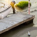 Wooden dock with a boat parked next to it and a white bird in the water.