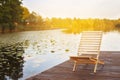 Wooden dock with lounge chair on pier on the calm lake in the middle of the forest Royalty Free Stock Photo