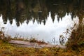 wooden dock plank on lake bank with trees reflection in water on an autumn day Royalty Free Stock Photo