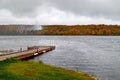 Wooden dock on the Superior lake surrounded by yellowing trees on a gloomy day in autumn in Michigan Royalty Free Stock Photo