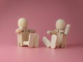 2 Wooden doll sitting and talking gestures on a pink background