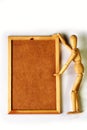 Wooden doll on white background, mannequin, pointing with its hands at a wooden frame with blank space inside Royalty Free Stock Photo