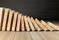 Wooden domino stones pyramid on wood floor falling over chain reaction
