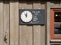 Wooden door with adjustable clocks hands and sign "fresh from the smoke, trout, char, whitefish"