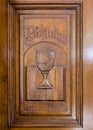 Wooden door with christian symbols: Bible and medieval cup