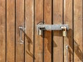 The wooden door in natural color is locked with two padlocks. Painted with colorless varnish. Hanging metal hooks. Close-up Royalty Free Stock Photo