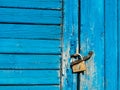 The wooden door with peeling blue paint is locked with a padlock Royalty Free Stock Photo