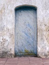 Wooden door with peeling blue paint texture on grungy plaster wall Royalty Free Stock Photo