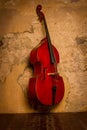 Wooden double bass on the background of an old Sepia wall on a wooden floor with stand and strings, Royalty Free Stock Photo