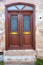 A wooden double door, with dark brown windows with a stone wall