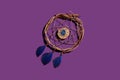 wooden dream catcher with feathers on a purple background